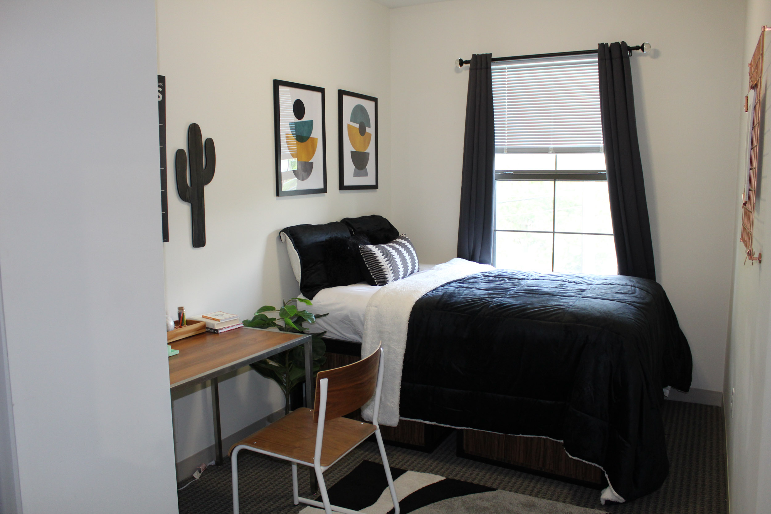 Landmark college park bedroom furnished with a bed, desk, chair, and dresser, and window