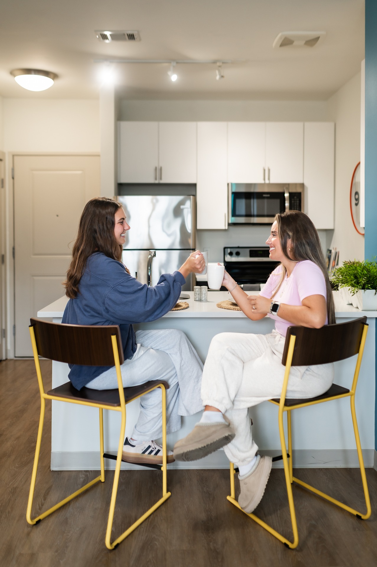 two girls sitting at landmark college park apartment cheering and laughing