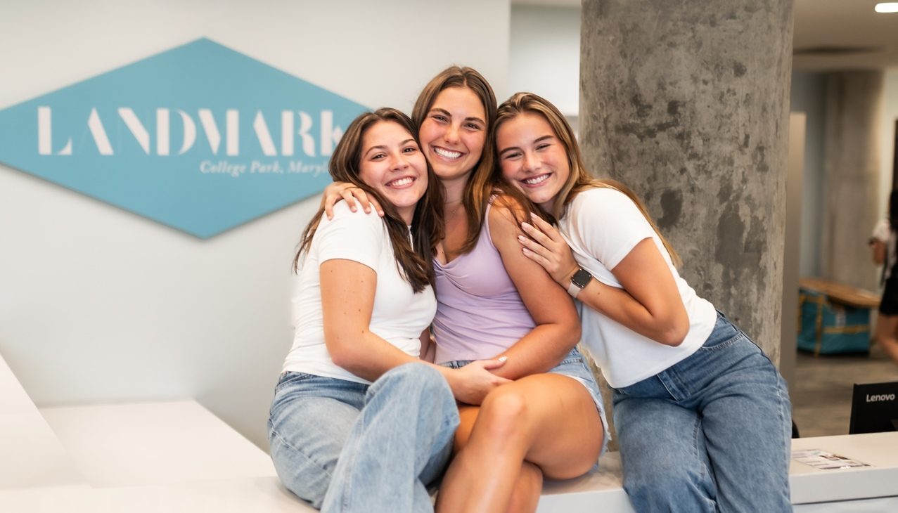three girls smiling and posing for the camera in lobby of landmark college park