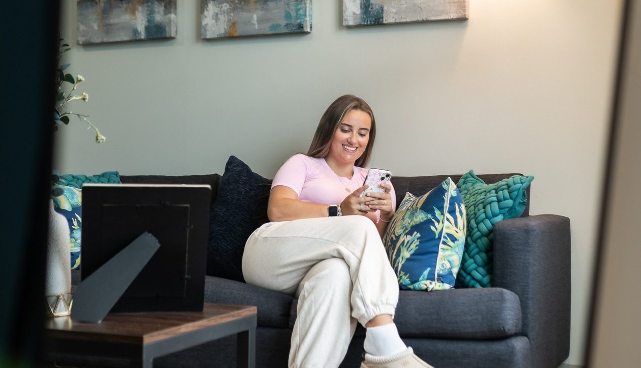 one girl sitting on the couch in her apartment at landmark college park