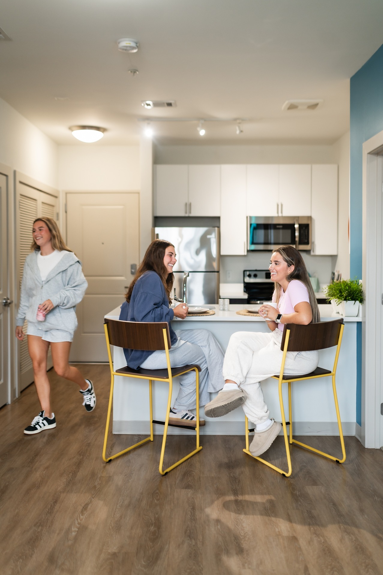 three girls sitting at landmark college park apartment cheering and laughing