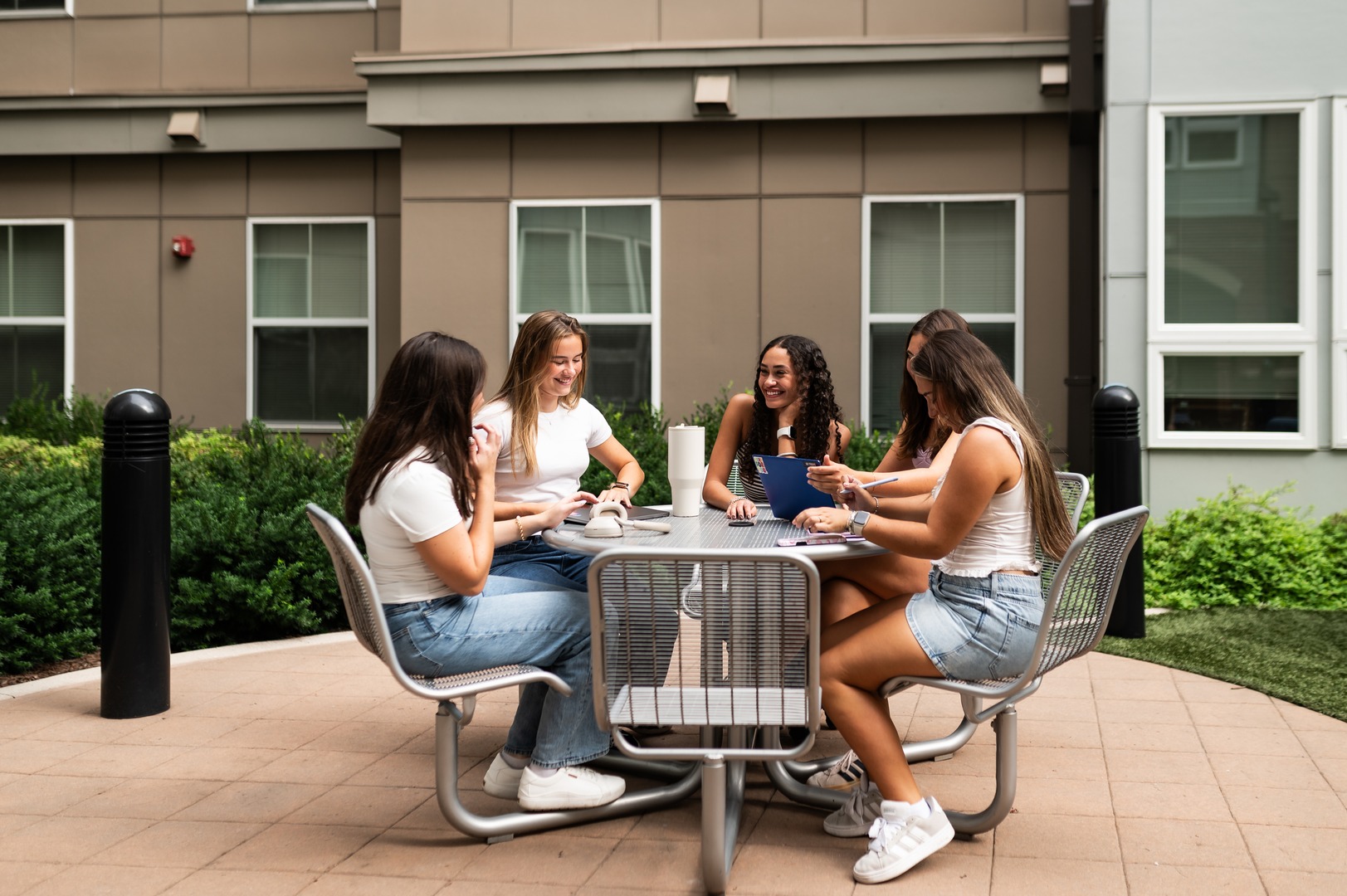 four girls sitting and smiling while studying outside at landmark college park